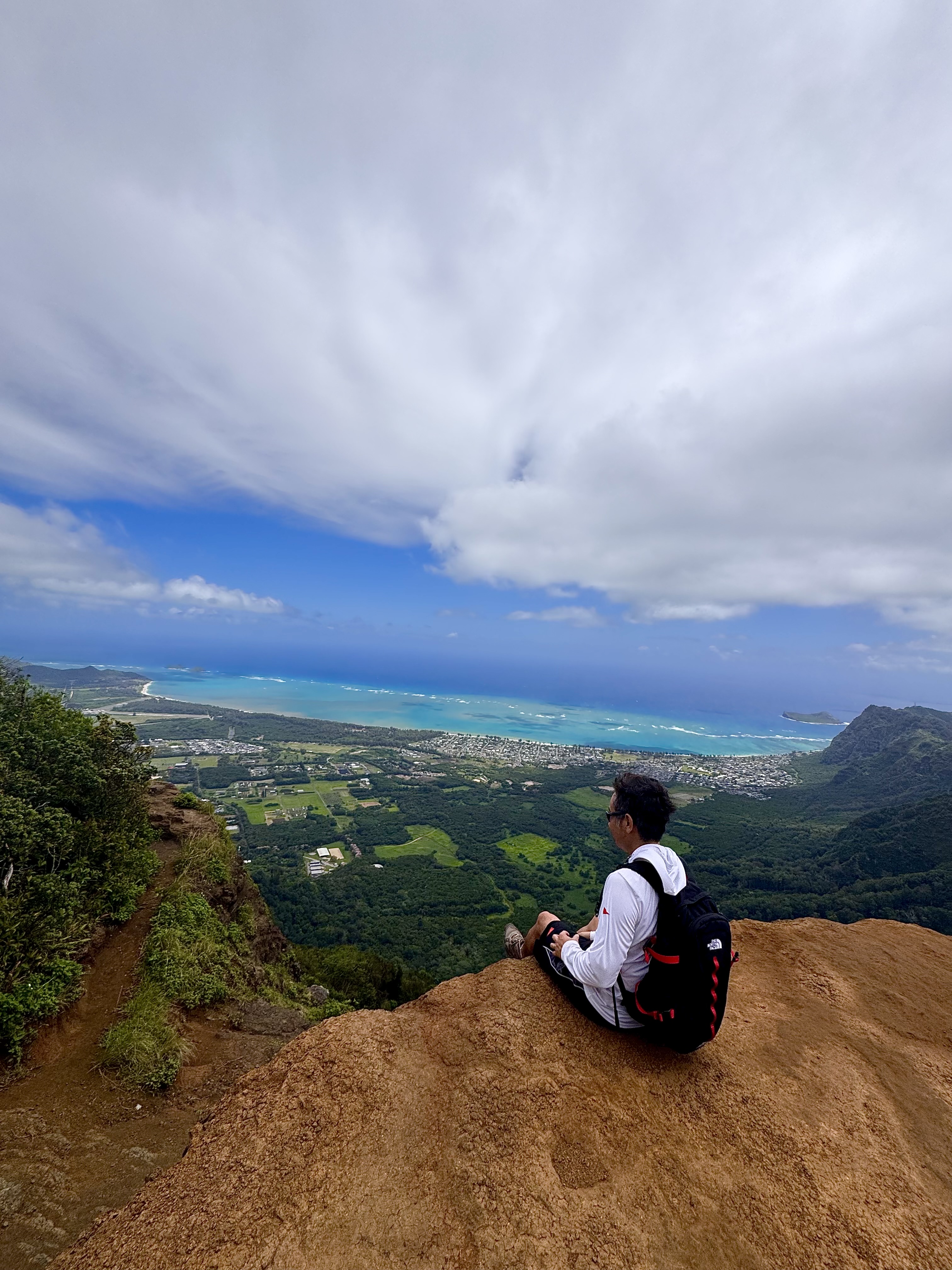John sitting on the edge of the cliff at the Kuliouou Ridge summit