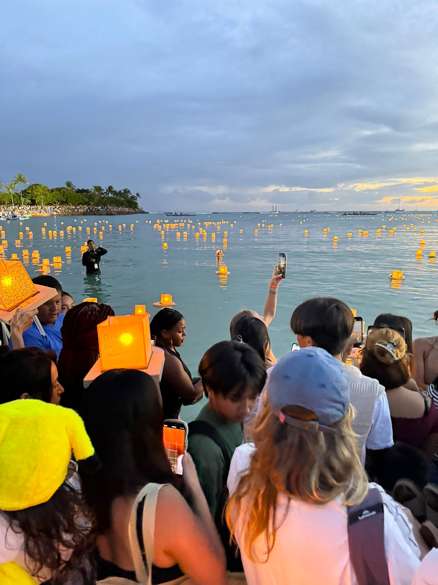 Glowing paper lanterns floating on the ocean at dusk during Lantern Floating Hawaii at Ala Moana Beach
