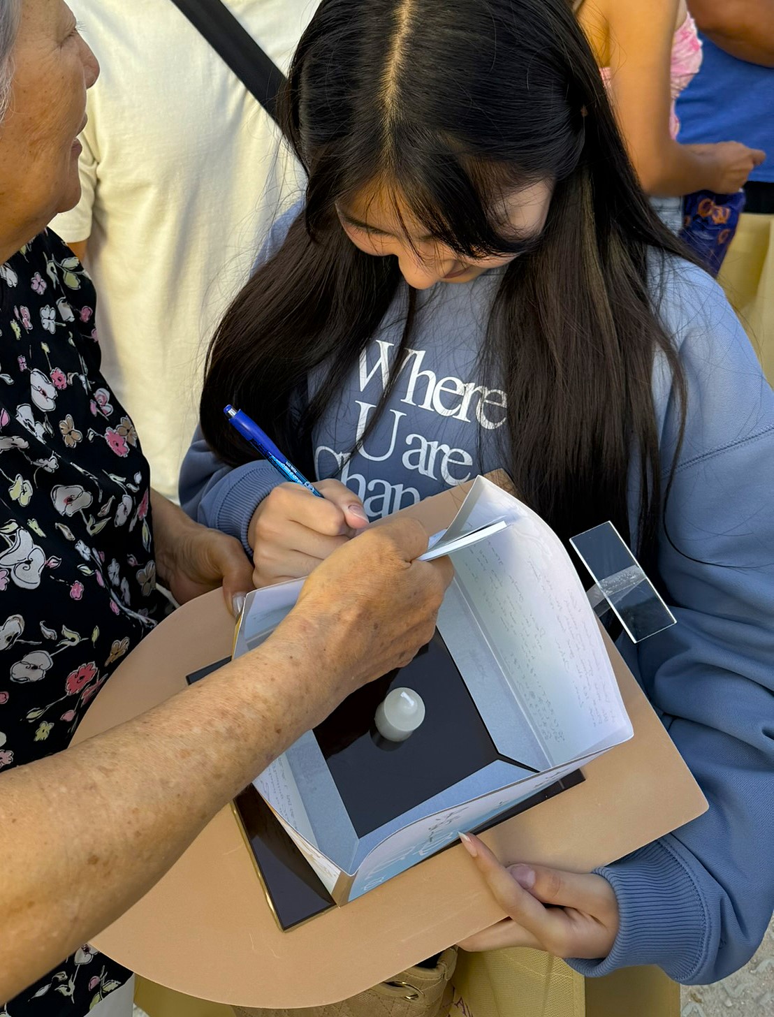 Maile writing a message on the lantern panel, concentrating carefully with a pen