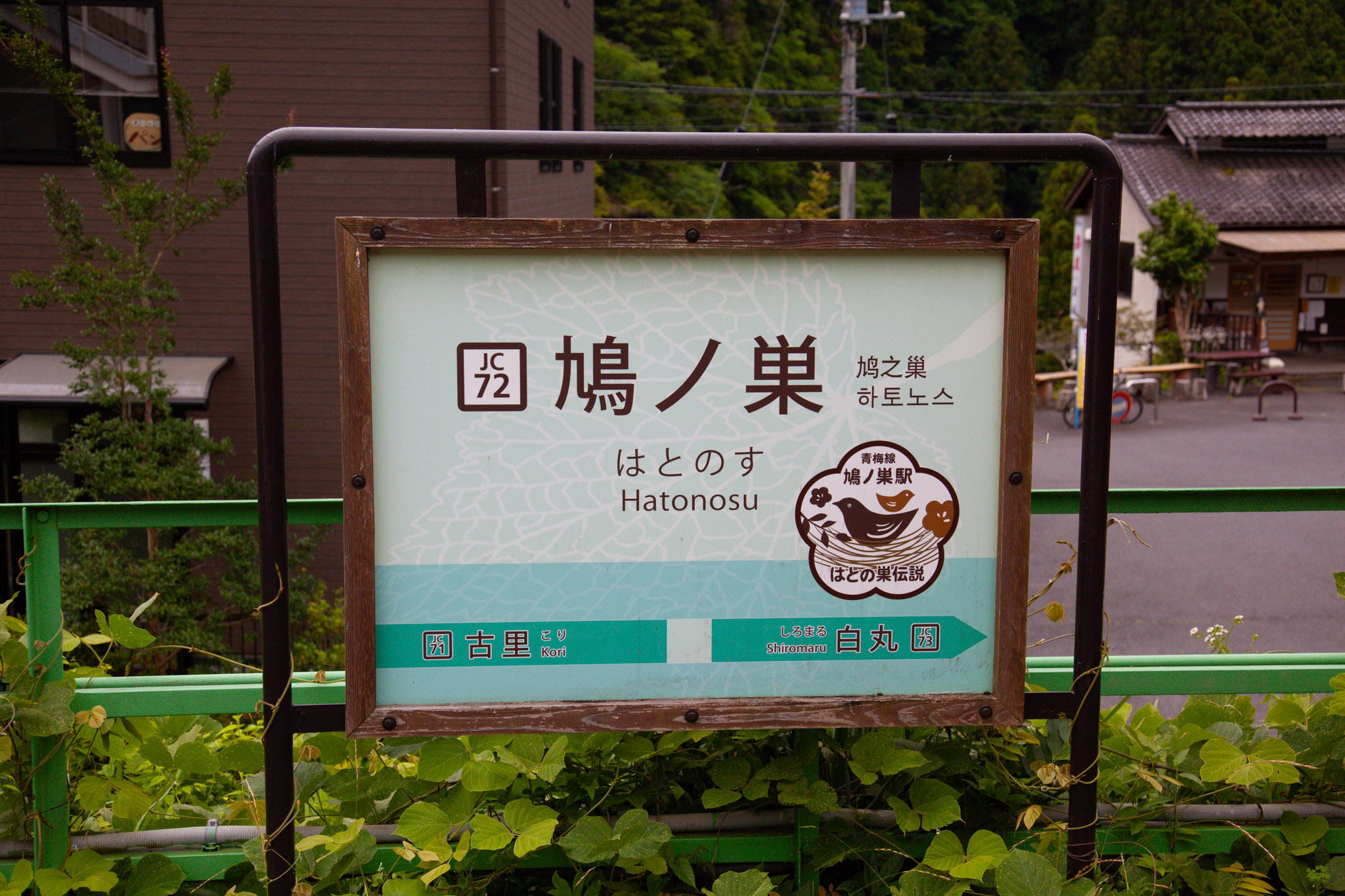 The Hatonosu station name sign — 鳩ノ巣 in large kanji with はとのす and Hatonosu beneath, station code JC72, green mountains behind