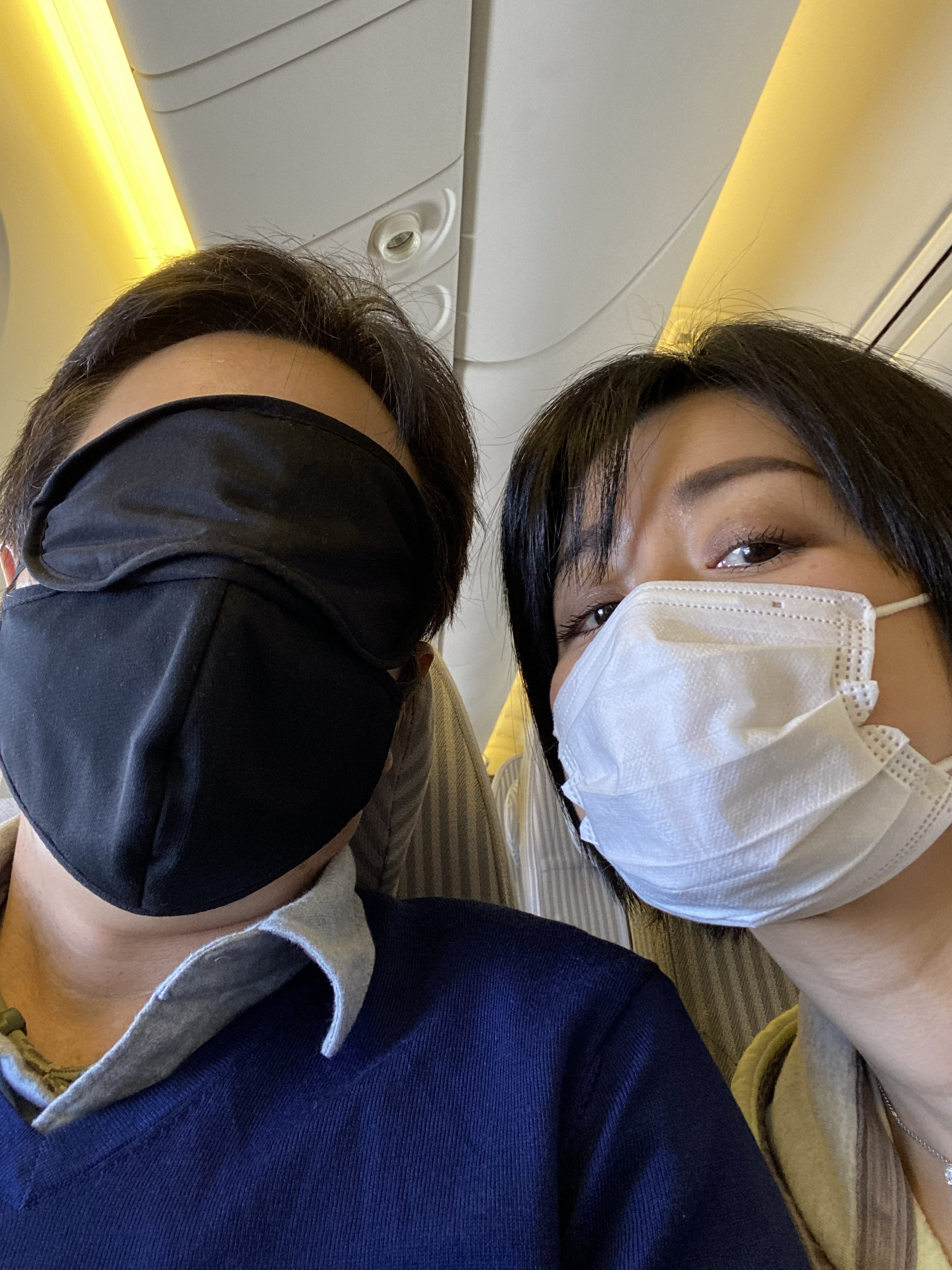 John and Ayumi wearing masks on the flight from Haneda to Kumamoto, December 2020 — John in a black mask and navy top, Ayumi in a white KF94 mask