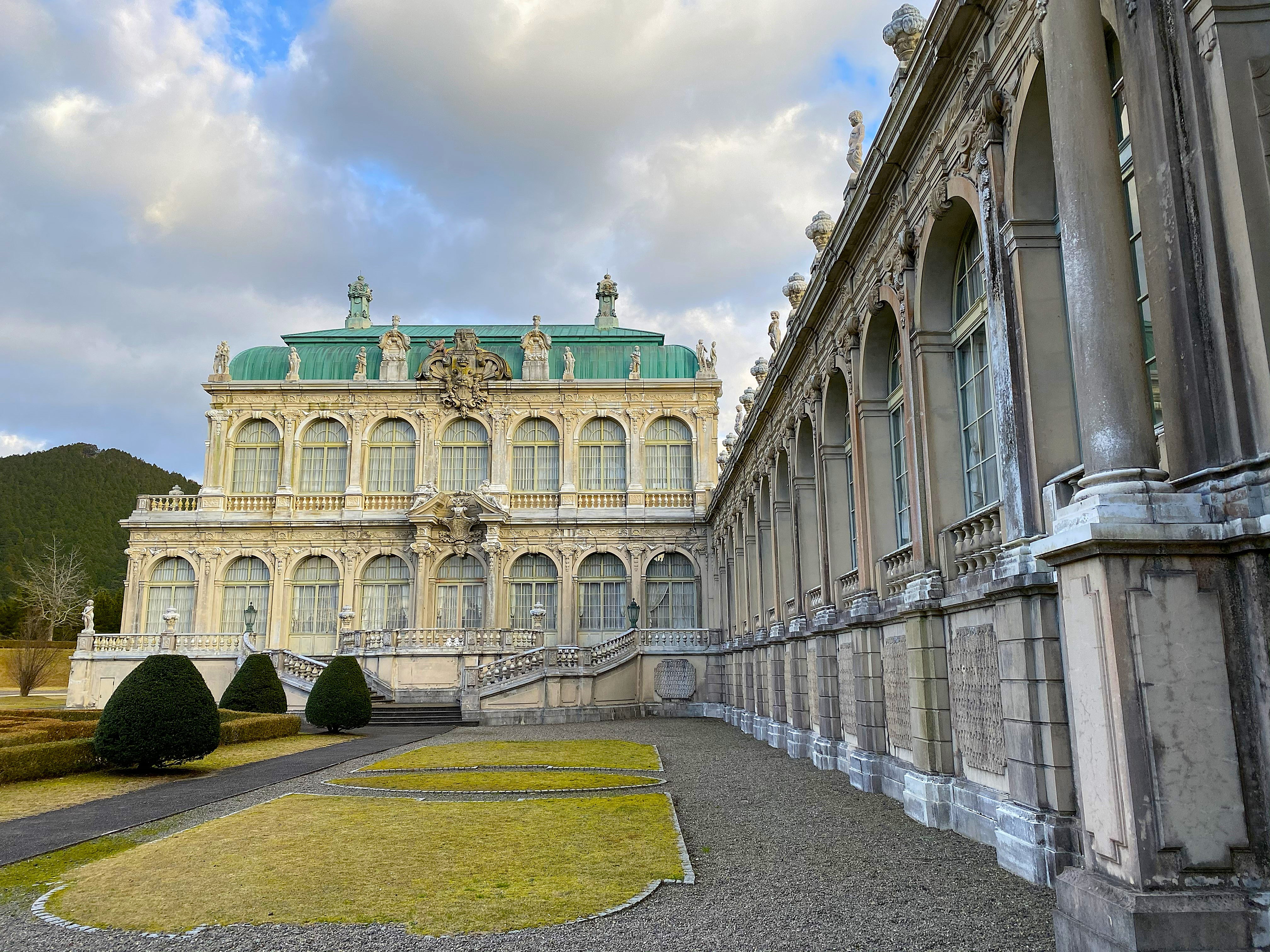 The full-scale replica of the Dresden Zwinger Palace at Arita Porcelain Park in Saga — elaborate baroque stone façade with formal gardens in front, mountains behind