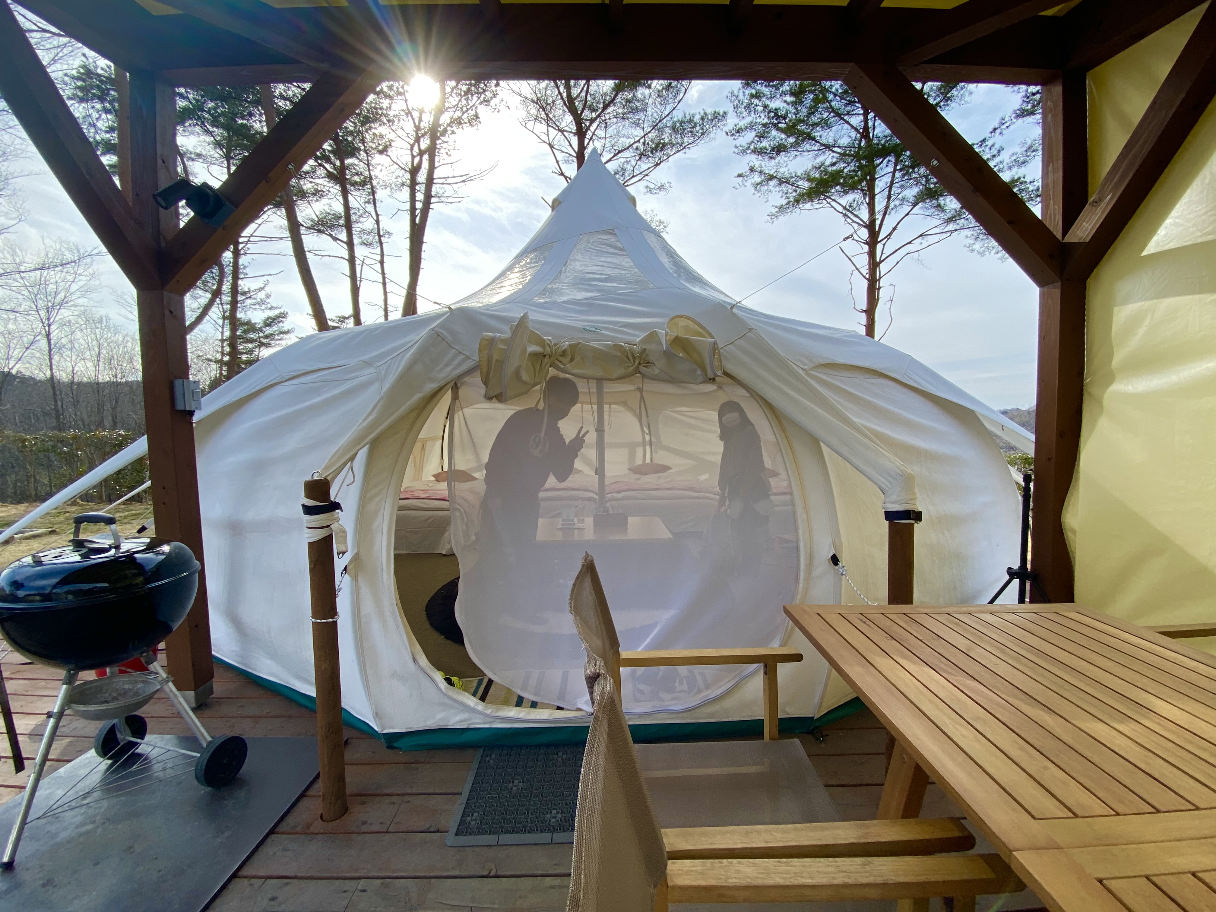 Two silhouettes visible through the translucent white canvas of the lotus tent, backlit by afternoon sun