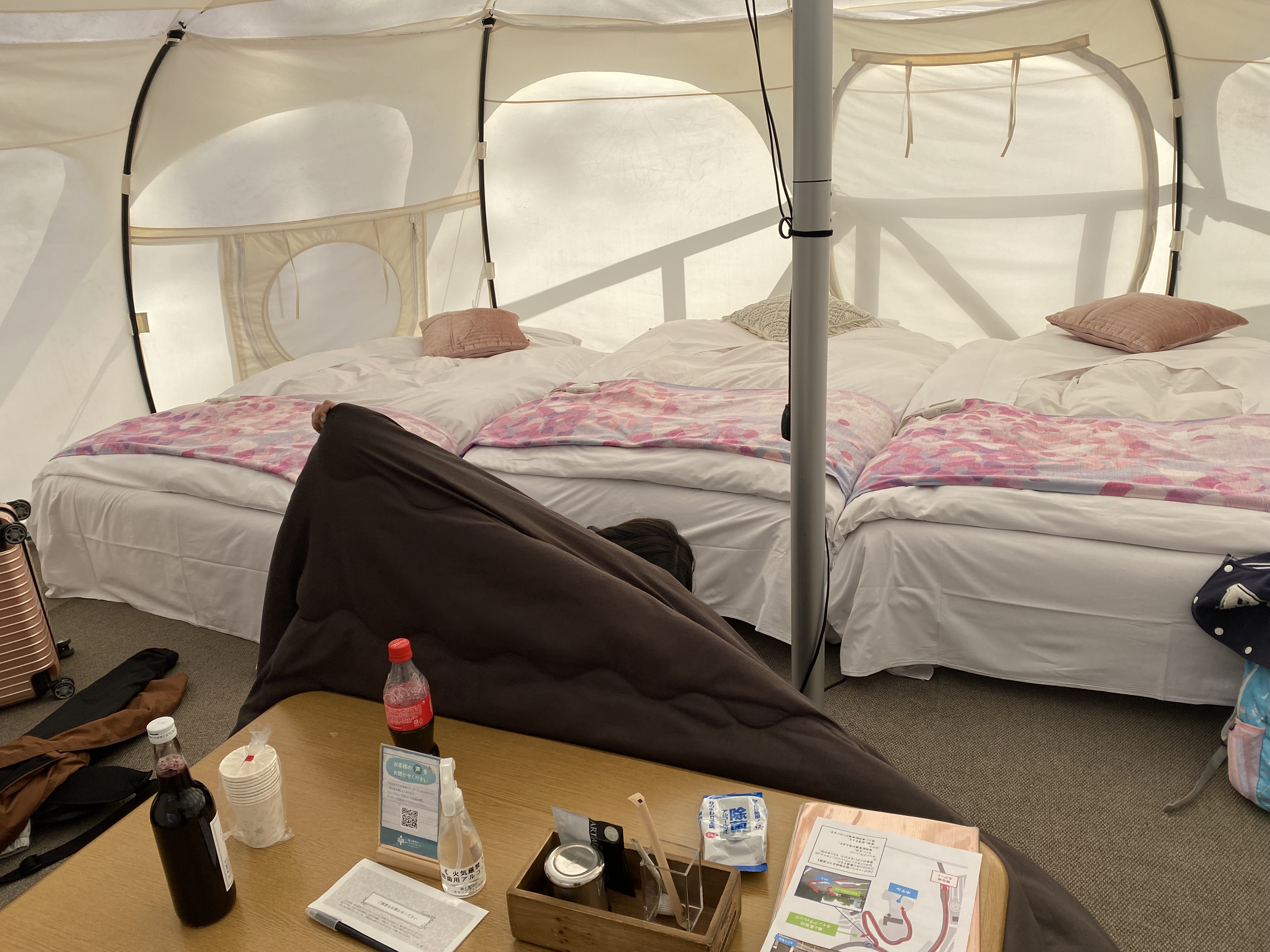 Inside the lotus tent — two large beds with duvet covers, a bean bag chair, coffee table, and amenities laid out neatly