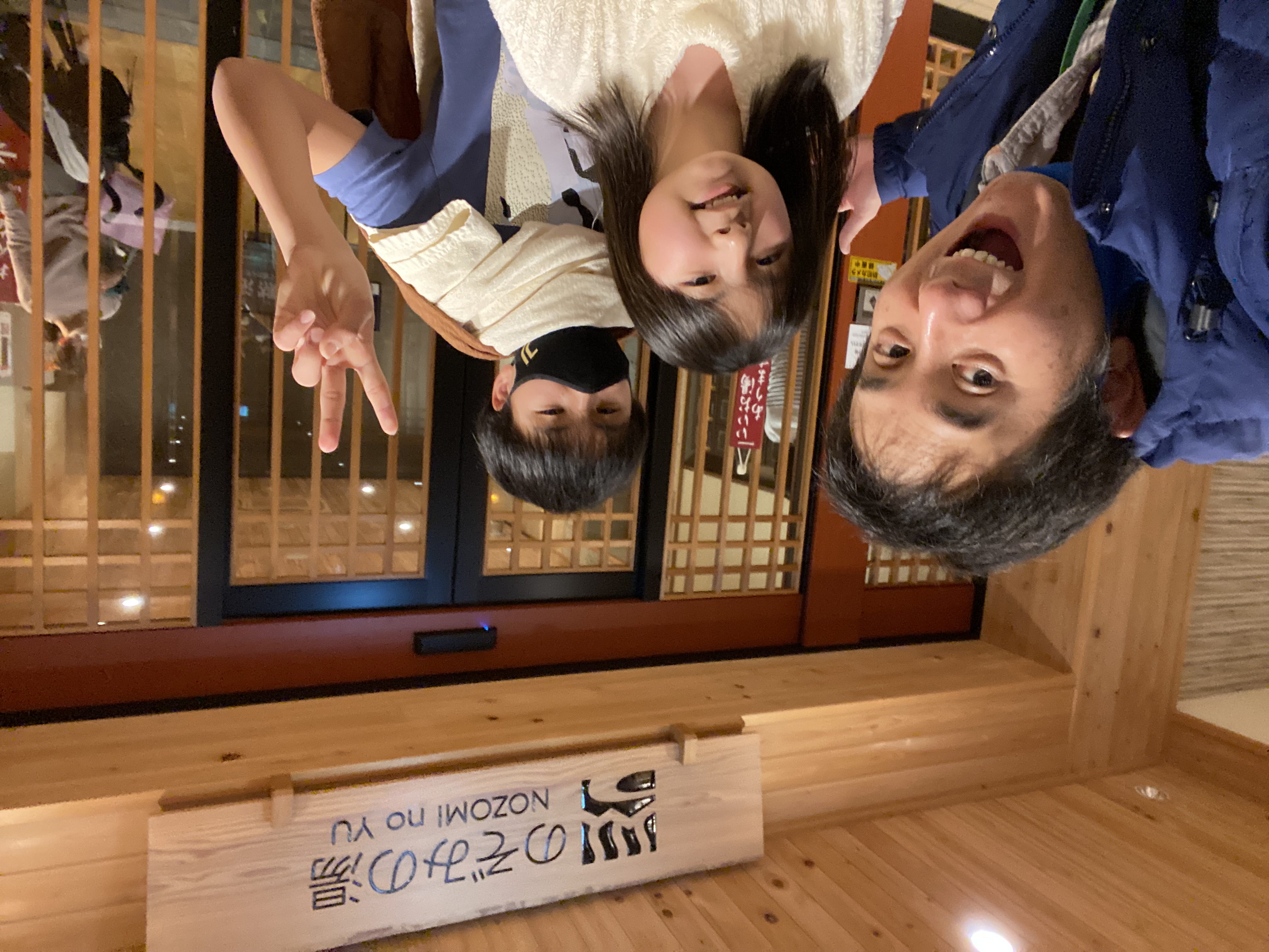 John, Jace, and Maile smiling for a selfie in front of the Nozomi no Yu onsen entrance sign