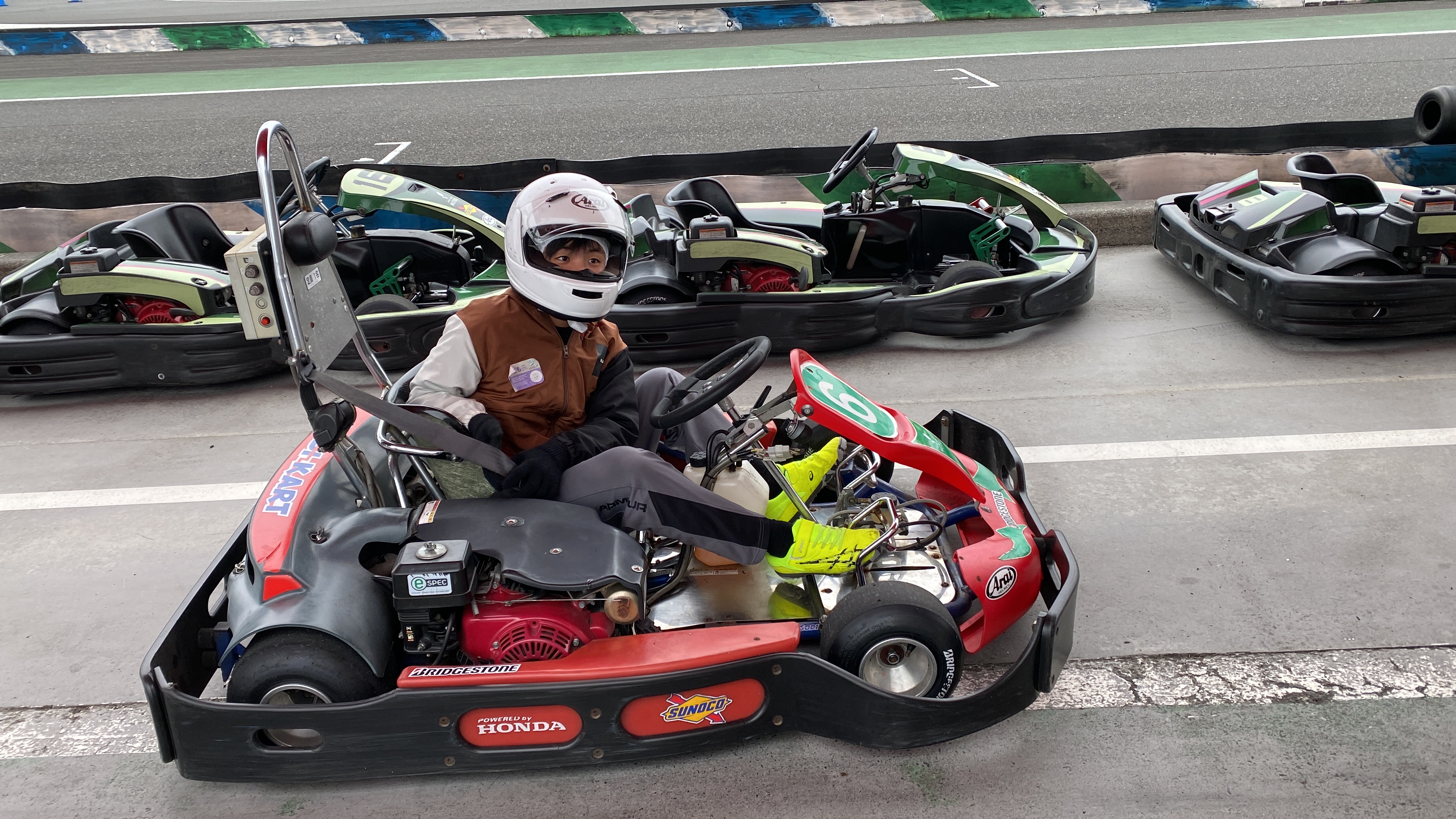 Jace in a white Arai helmet sitting in a Honda-powered go-kart on the Motegi circuit, ready to race