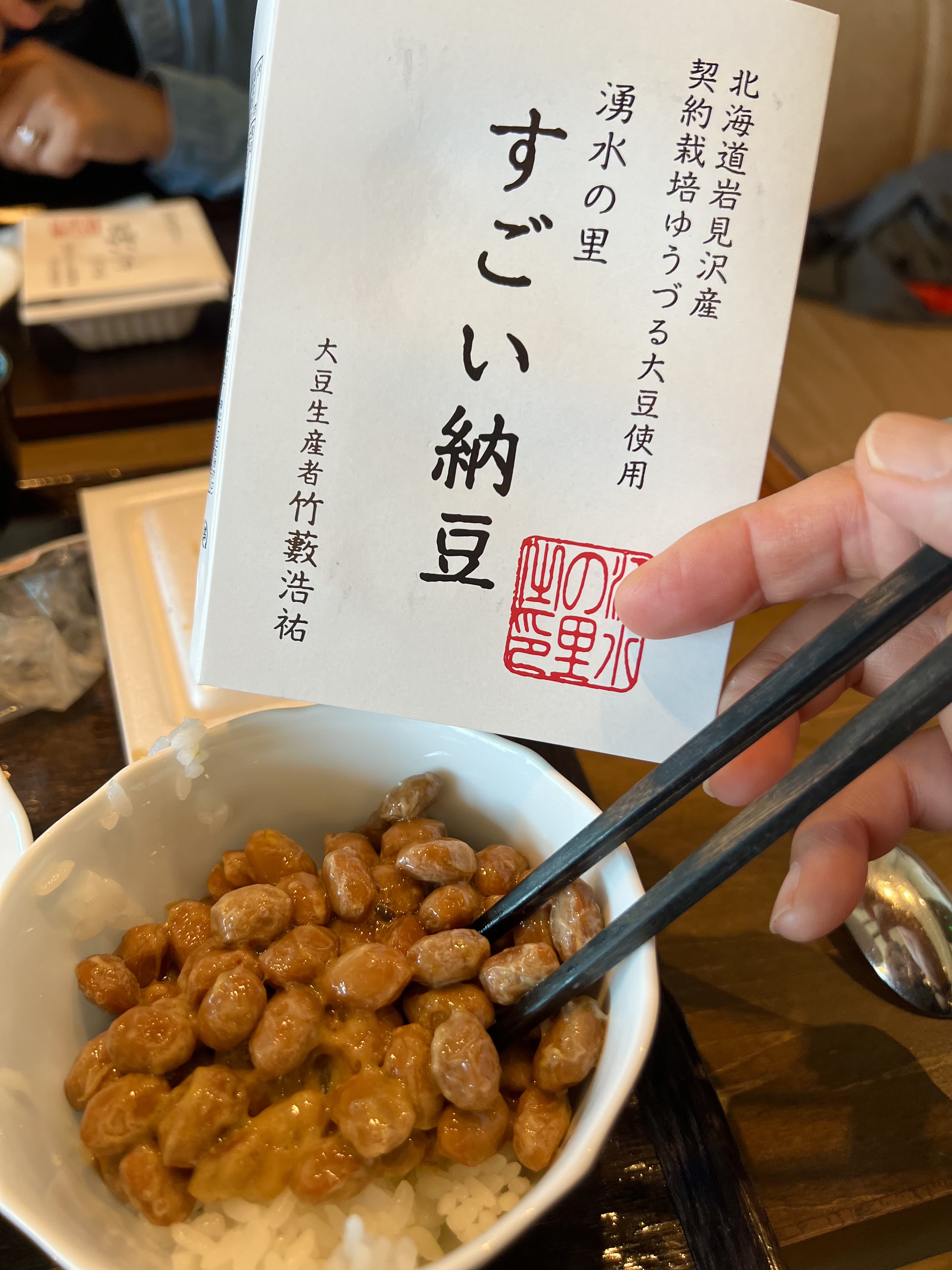 Park Hyatt Niseko breakfast — a bowl of Sugoi Natto from Iwamizawa, Hokkaido, with the producer's packaging card held up alongside it