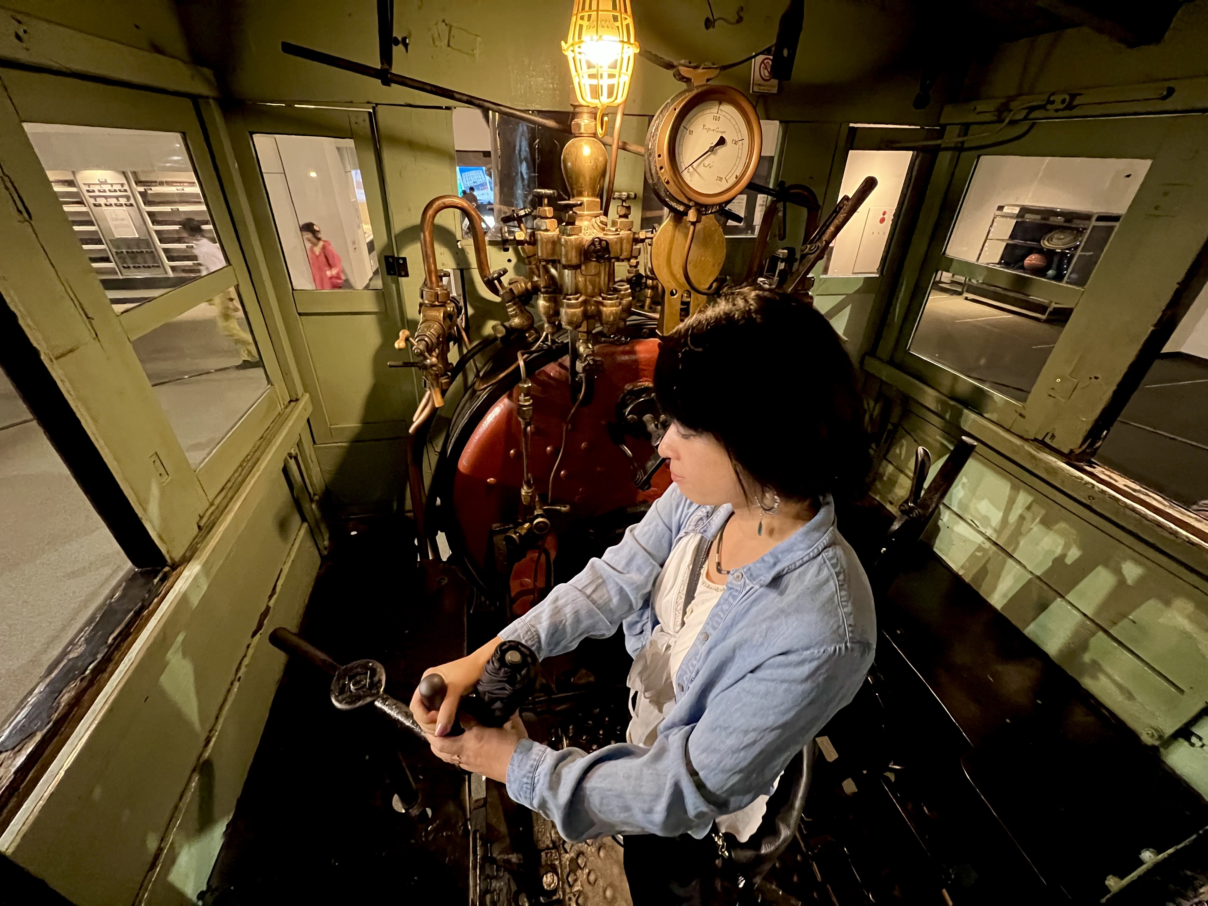 Ayumi in the cab of a restored locomotive at the Otaru Museum, surrounded by brass gauges and original controls