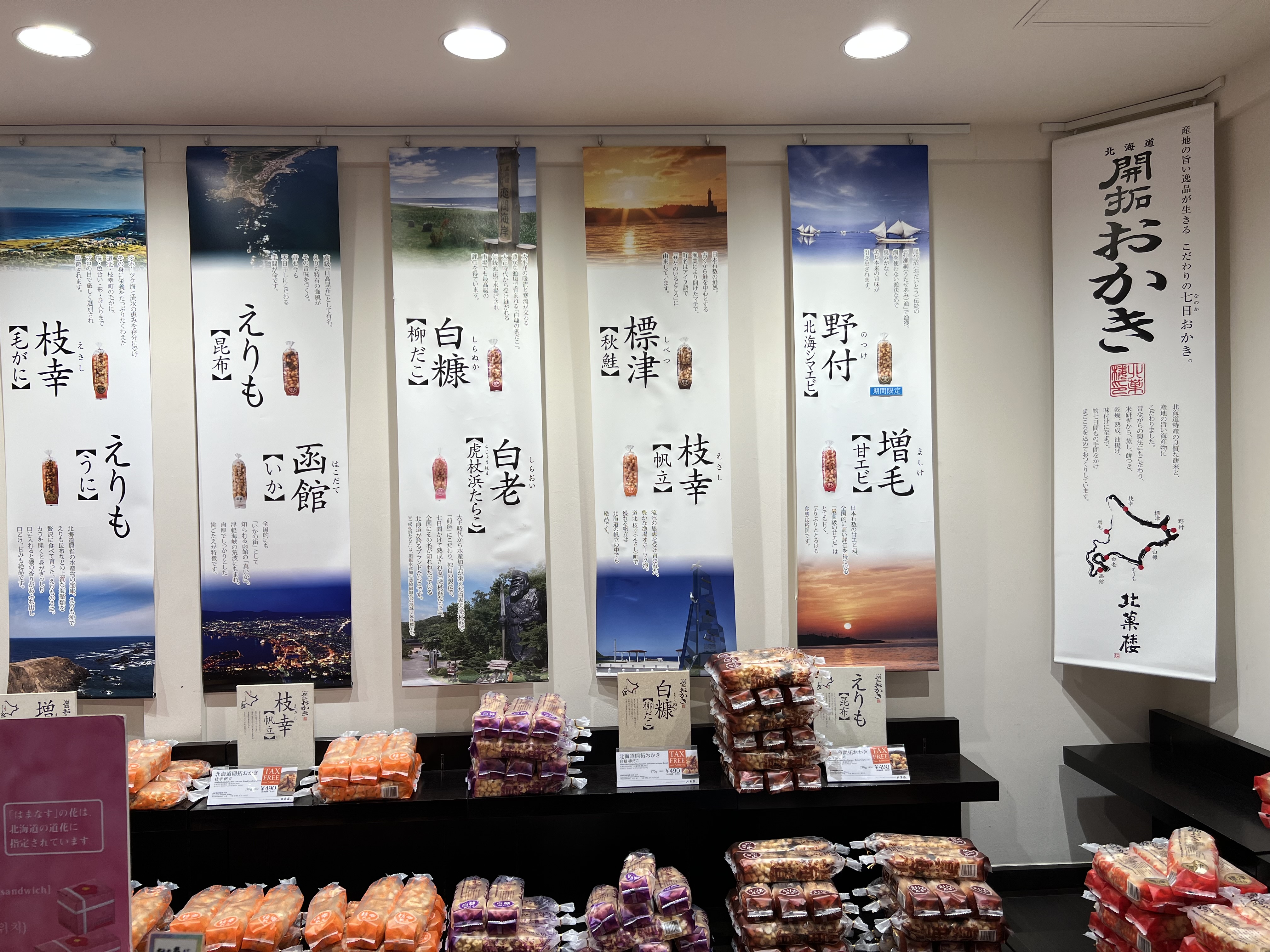 Kitakaro in Otaru — a wall of Hokkaido regional snack banners behind the display cases
