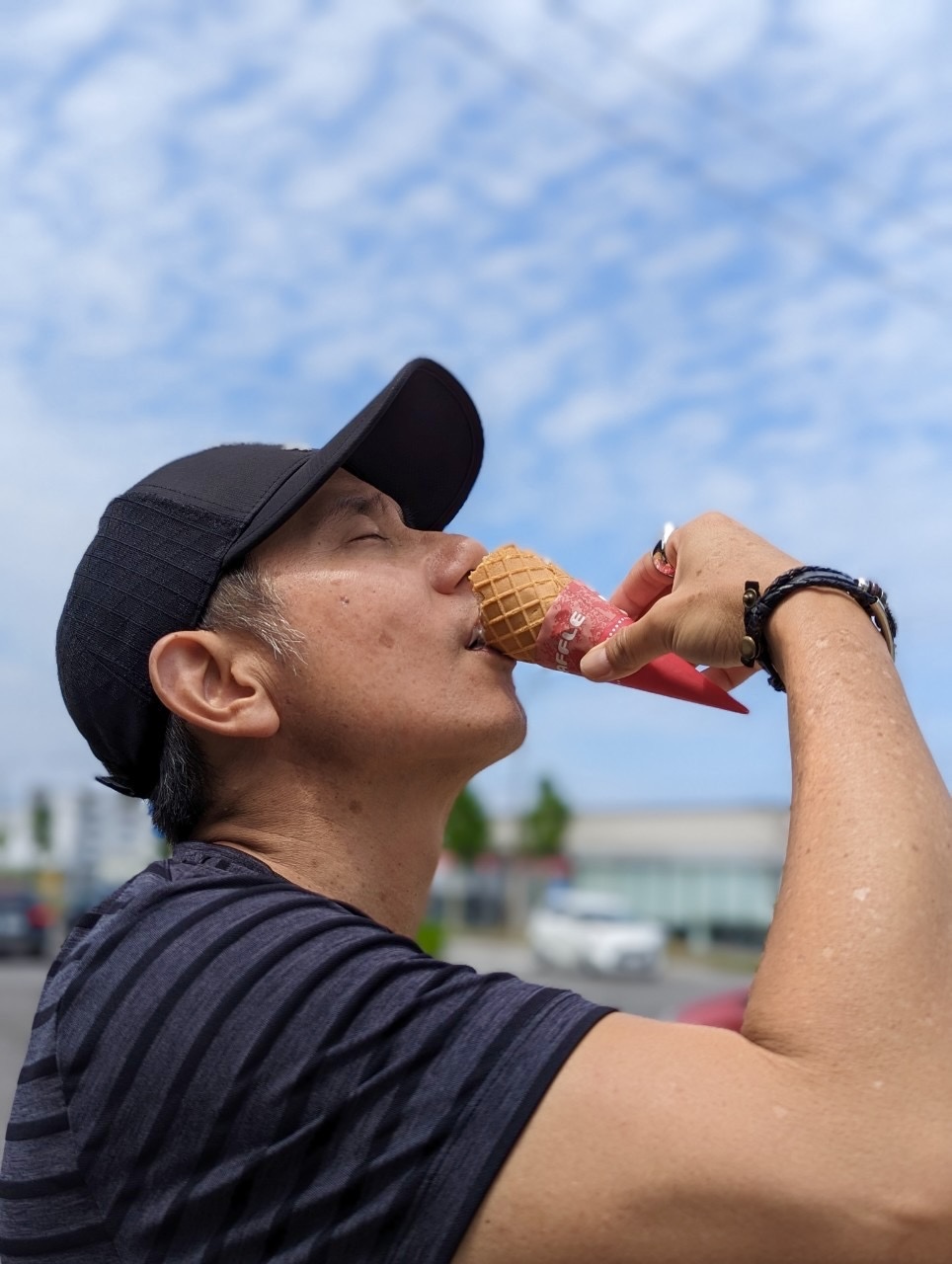 John finishing the last of a Kitakaro soft serve cone, profile shot against a blue Hokkaido summer sky