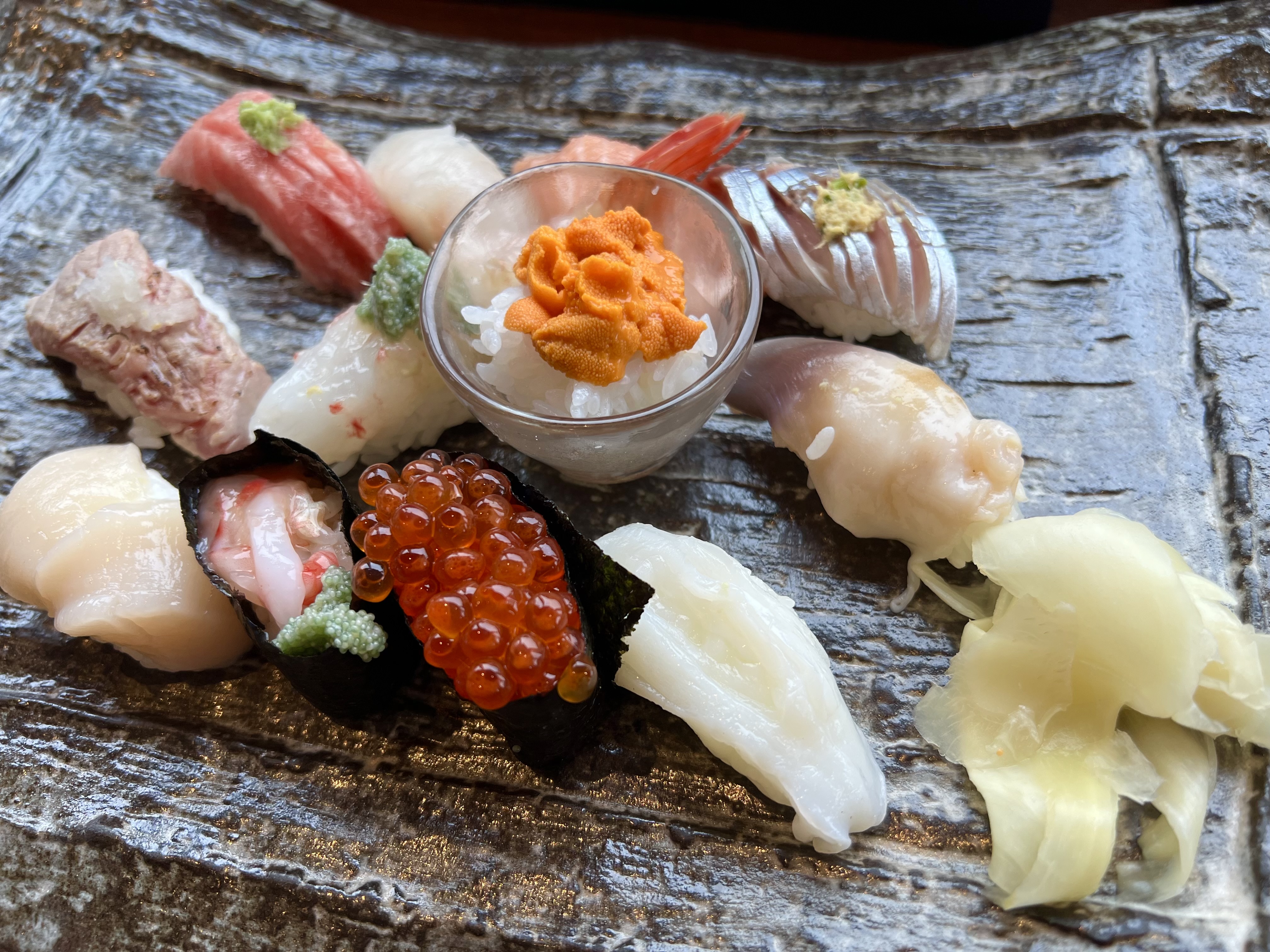 Otaru sushi spread at Masazushi — uni, ikura gunkan, scallop, tuna, crab, squid and more on a textured slate plate